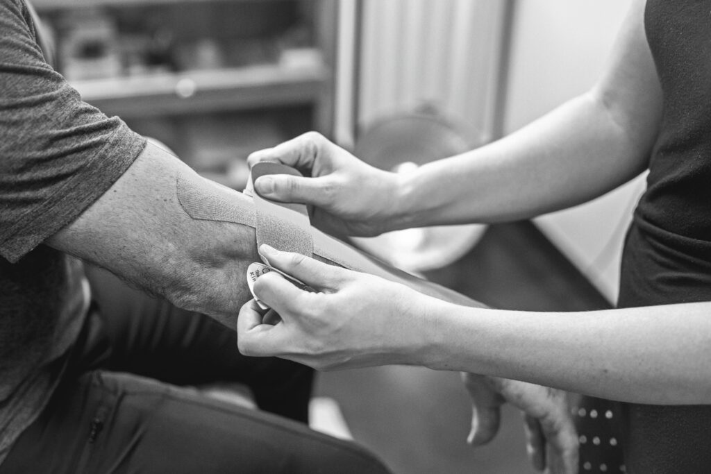 Patient recevant une application de ruban thérapeutique KT Tape pour une tendinite du coude (tennis elbow) dans une clinique chiropratique à Longueuil